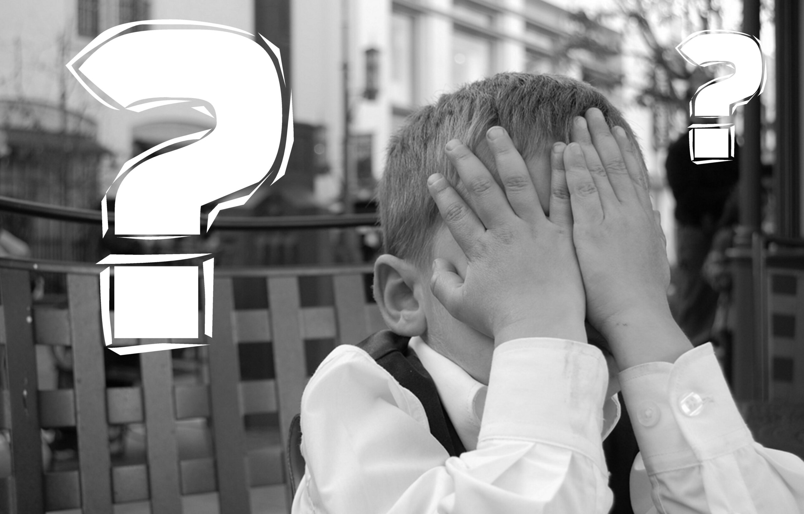 Boy covering his hands and two question marks